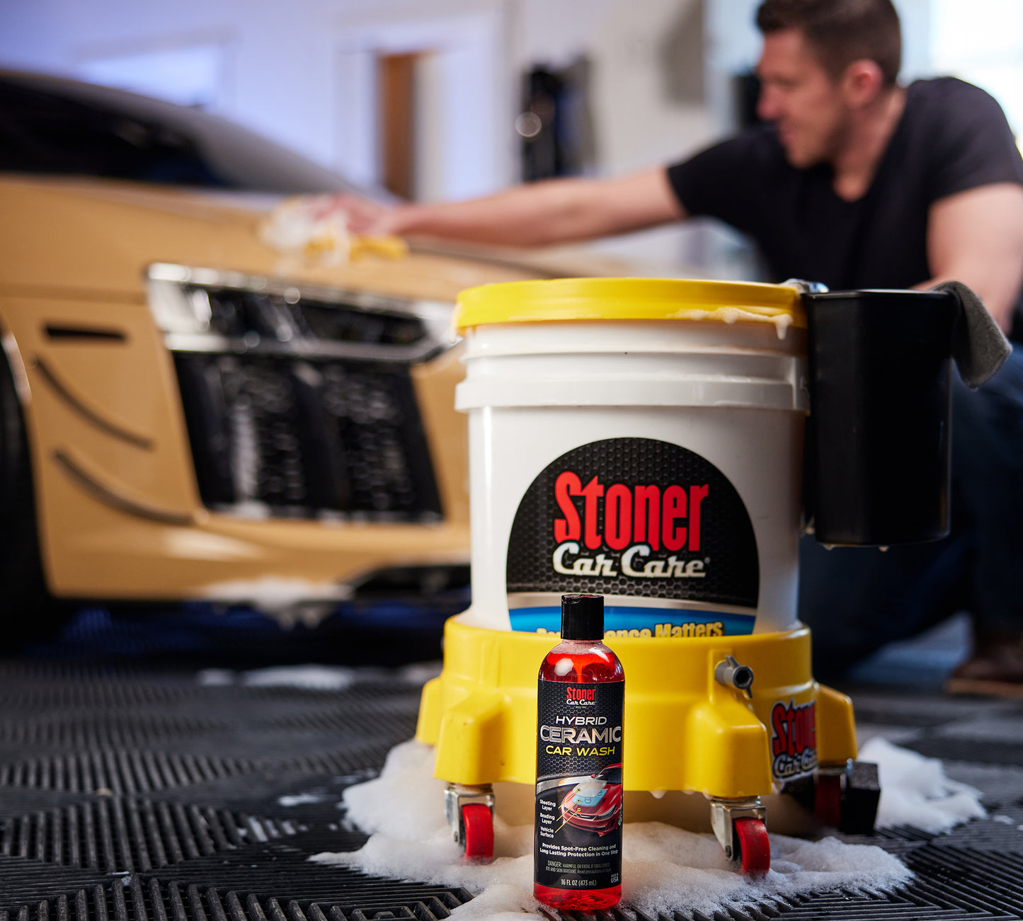 Stoner Hybrid Ceramic Car Wash 16oz posed in front of a man cleaning a car