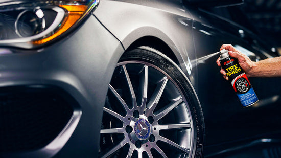 Person applying tire dressing to a car tire with a spray can.