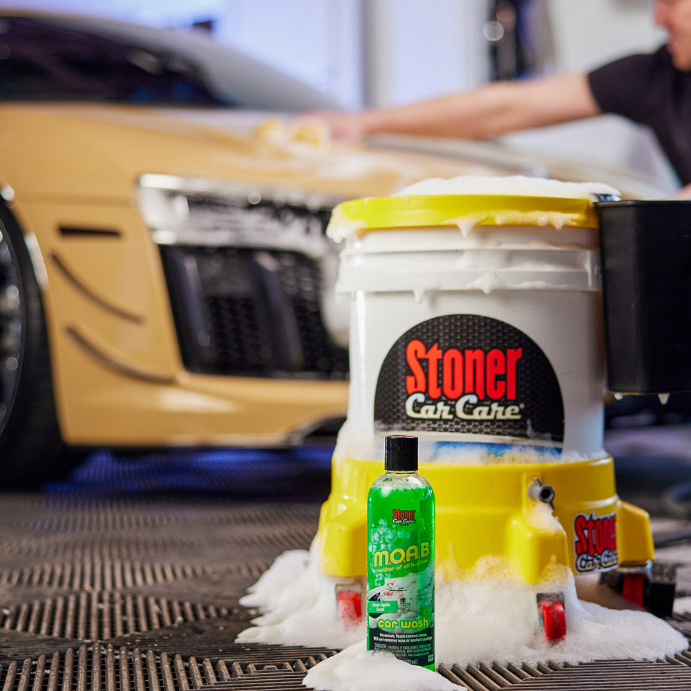 Car care products including a 'Stoner Car Care' bucket and 'MOAB' bottle with a car in the background.