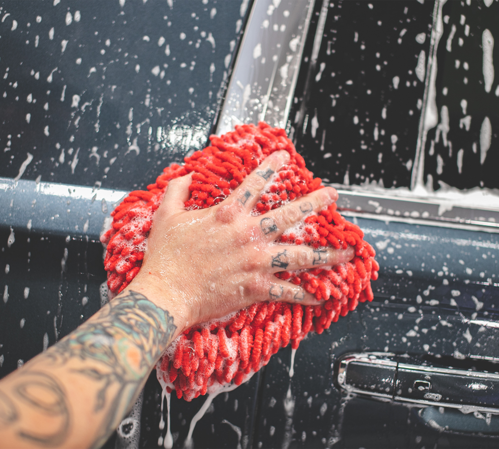 
                  
                    A man using the Chenille Microfiber Knobby Wash Mitt to clean the exterior of a car with soap
                  
                