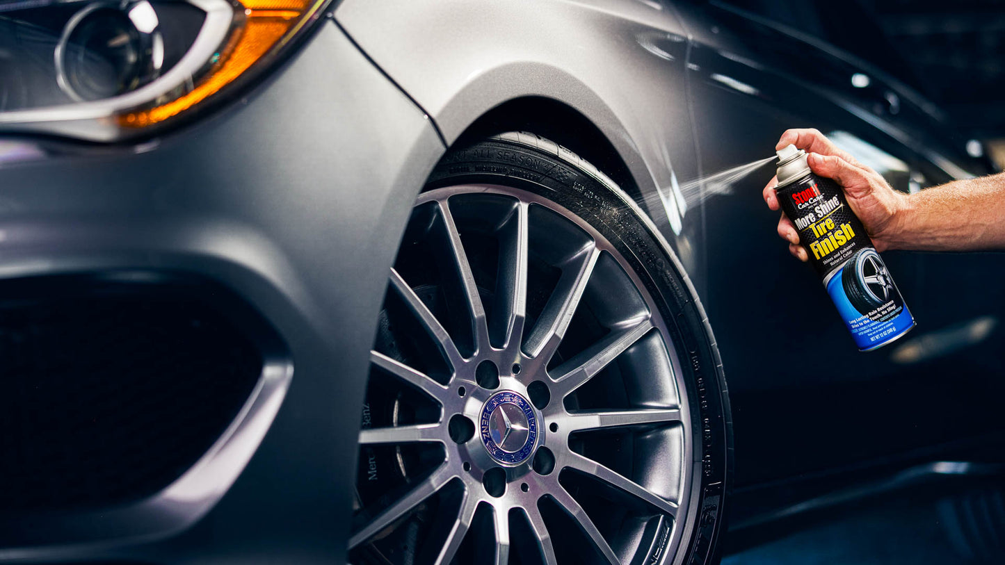 Person applying a product to a car wheel with a close-up of the wheel and car body.