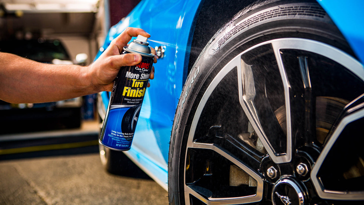 Person holding a can of tire shine spray next to a blue car wheel.