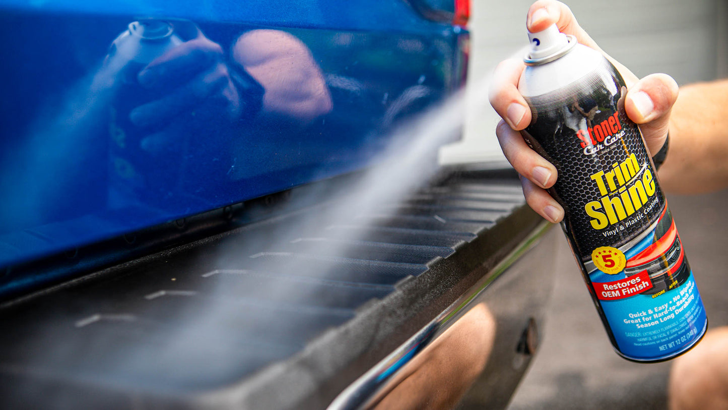 Person using a 'Trim Shine' spray can on a car's trim.