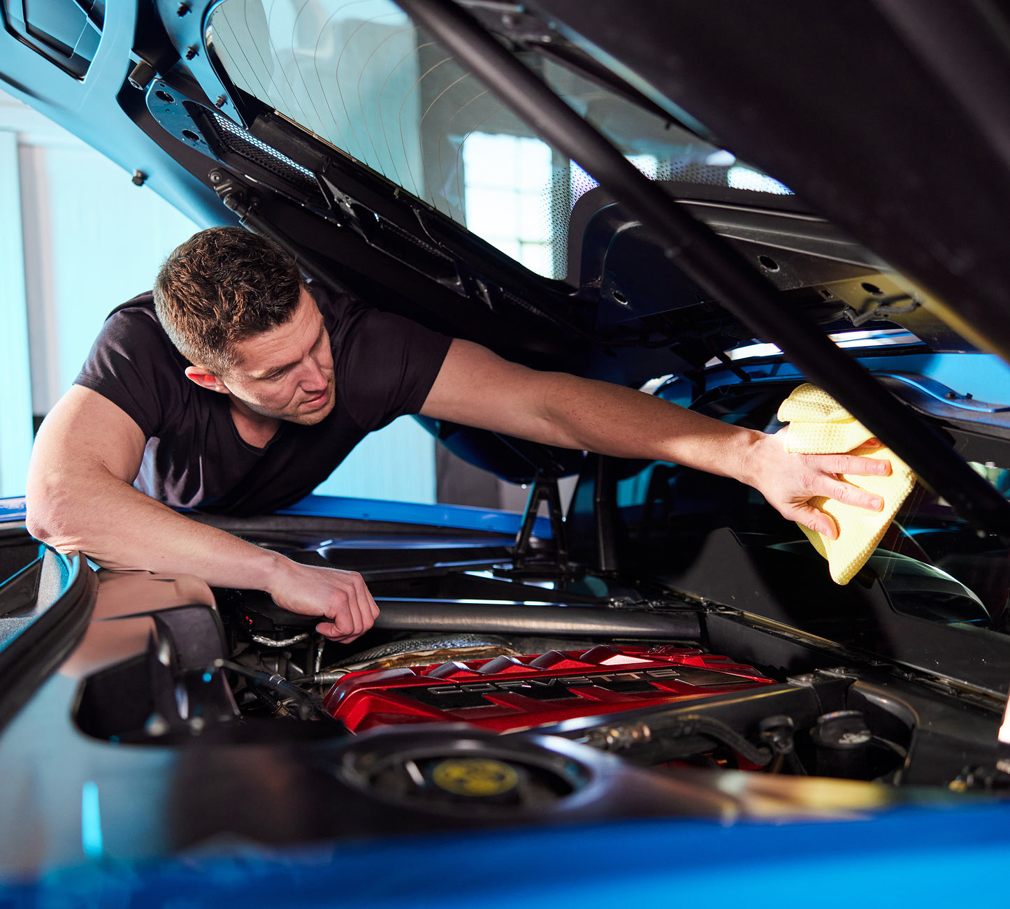 A picture of a man using the Premium Glass Microfiber – 16in X 16in - 370 GSM to clean the inside of a car